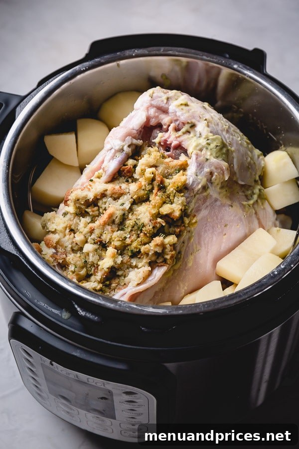 Juicy Instant Pot Turkey Breast with Homestyle Stuffing and Fluffy Mashed Potatoes 4 Peeled potato chunks and a raw, herb-buttered turkey breast stuffed with dressing, arranged inside an Instant Pot for cooking.