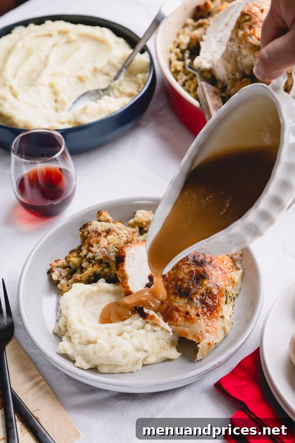 Juicy Instant Pot Turkey Breast with Homestyle Stuffing and Fluffy Mashed Potatoes 6 Rich, homemade turkey gravy being poured generously over a plate laden with sliced turkey breast, fluffy mashed potatoes, and savory stuffing.