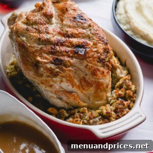 A dish of stuffing with a roasted turkey breast on top.