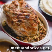 A dish of stuffing with a roasted turkey breast on top.
