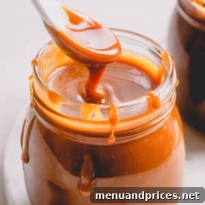 Mastering Dry Caramel Sauce 11 A jar of golden caramel sauce with a spoon lifting a scoop out.