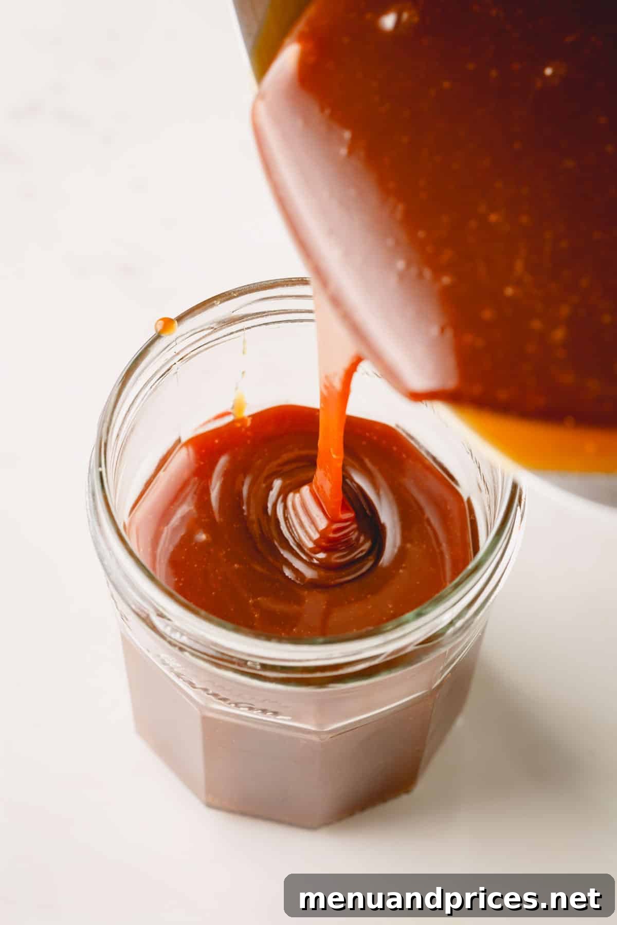 Mastering Dry Caramel Sauce 9 Warm homemade caramel sauce being carefully poured into a glass canning jar, ready for cooling and storage.
