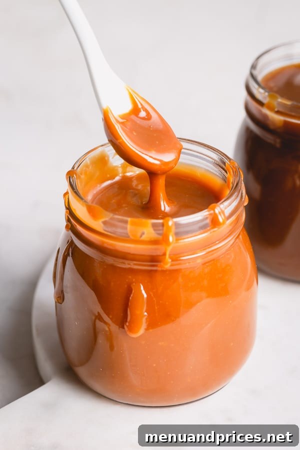 Mastering Dry Caramel Sauce 10 A beautifully presented jar of golden caramel sauce with a spoon lifting some out, emphasizing its appealing texture.