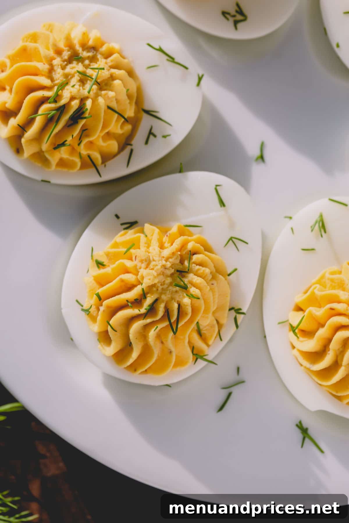 Simple Steps to Irresistible Deviled Eggs 2 Classic deviled eggs garnished with fresh dill on a pristine white platter, ready to be served.