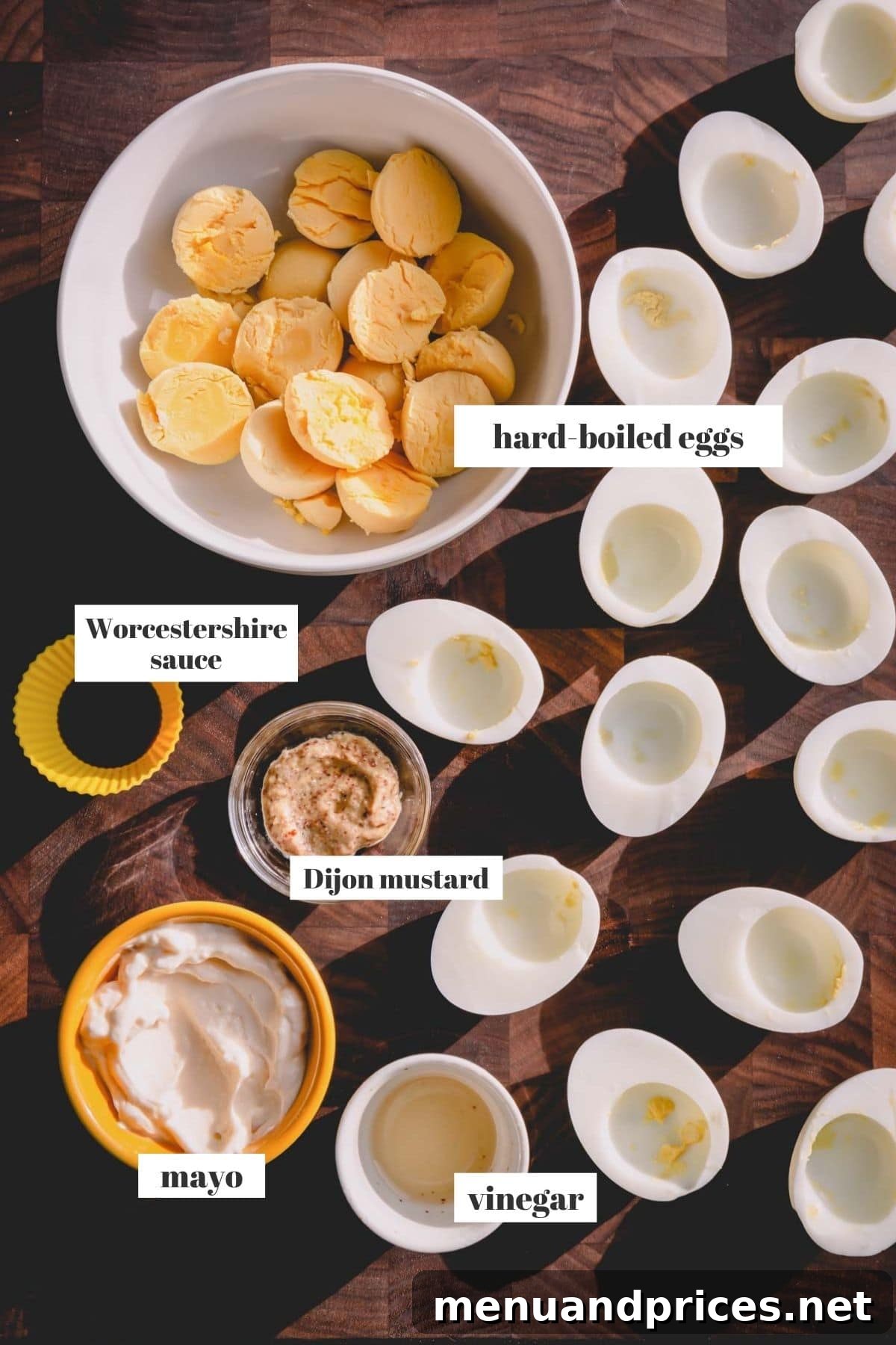 Simple Steps to Irresistible Deviled Eggs 3 A selection of key ingredients for deviled eggs, including fresh eggs, mayonnaise, Dijon mustard, apple cider vinegar, and Worcestershire sauce, artfully arranged on a dark wooden board.