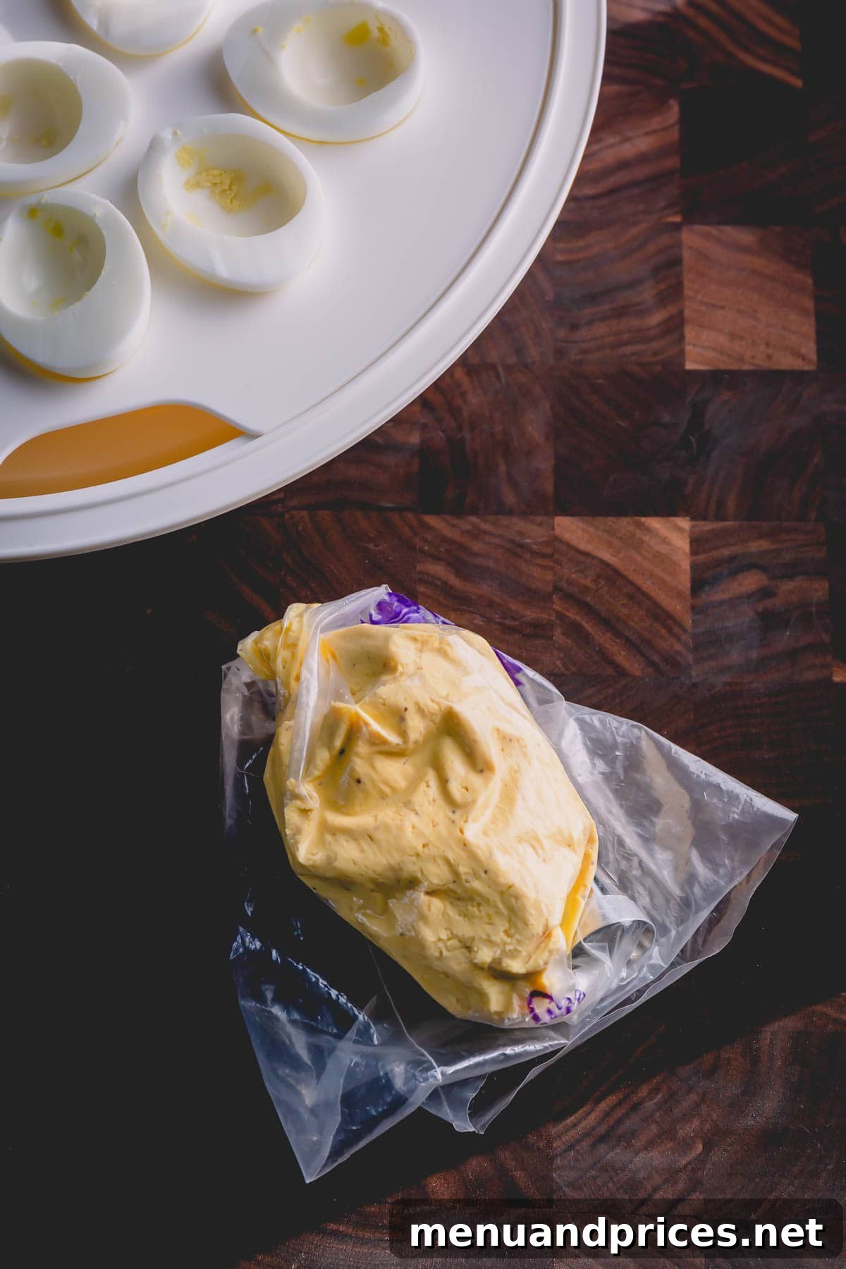 Simple Steps to Irresistible Deviled Eggs 7 Egg yolk mixture perfectly prepared in a piping bag, ready to be piped, alongside neatly halved egg whites arranged in a portable egg carrier.