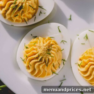 Classic deviled eggs garnished with fresh dill on a pristine white platter.