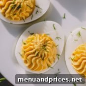 Close-up of classic deviled eggs, beautifully garnished with fresh dill on a white serving platter, appealingly presented.