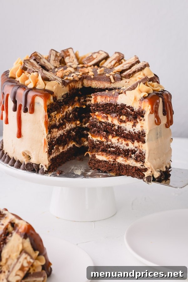 Snickers cake cut and a slice is being lifted with a spatula.