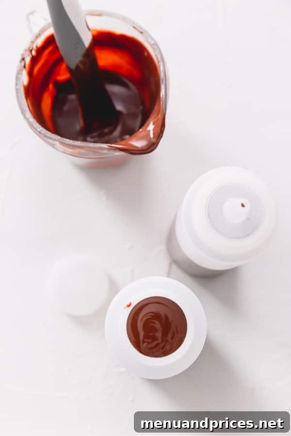 Chocolate ganache in a liquid measuring cup along with 2 plastic squirt bottles.