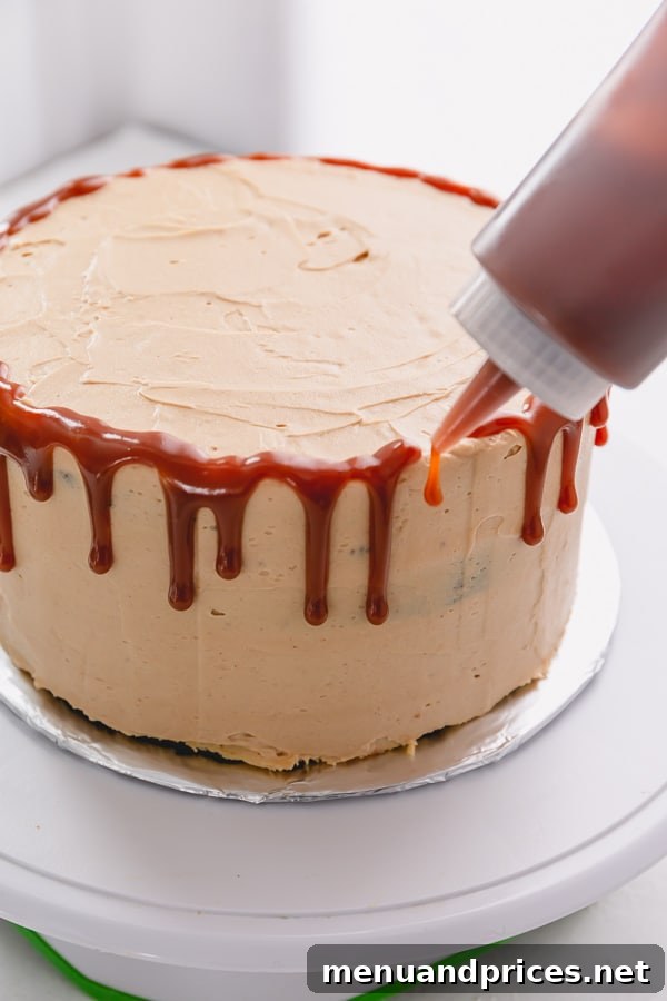 Caramel sauce is being drip along the edges of the cake from a plastic squirt bottle.