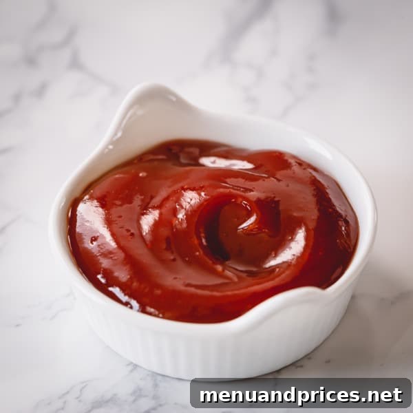 A small bowl of homemade spicy ketchup, featuring a rich red color and smooth texture, ready for dipping fries or nuggets.