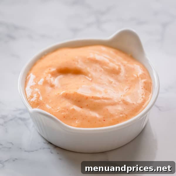 A small bowl of creamy horseradish mayonnaise sauce, with a hint of smoked paprika, perfect for grilled meats or seafood.