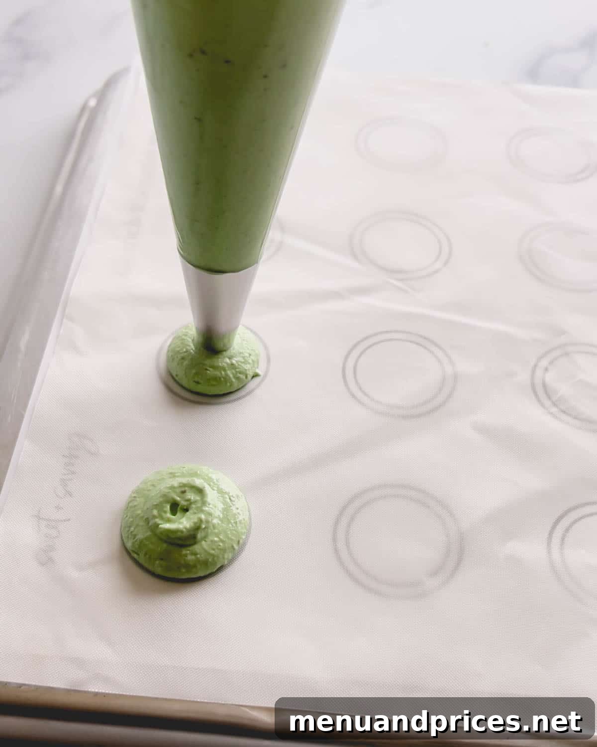 Minty Cocoa Macaron Bliss 12 Perfectly round, vibrant green macaron shells are being meticulously piped onto a white surface adorned with a circular pattern for guidance.