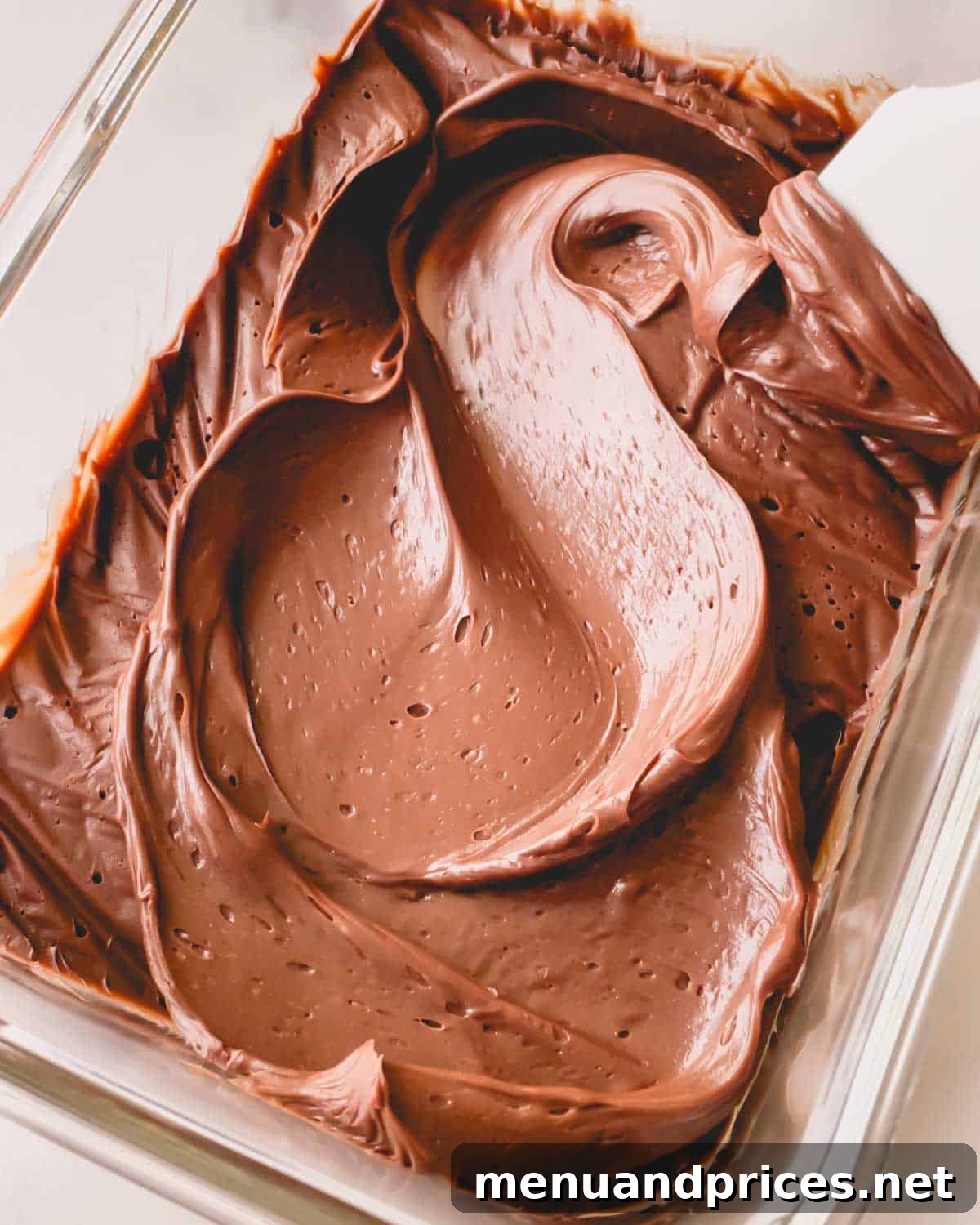 Minty Cocoa Macaron Bliss 16 Thickened chocolate ganache, swirled to perfection with a spatula, rests invitingly in a flat container, ready for piping.