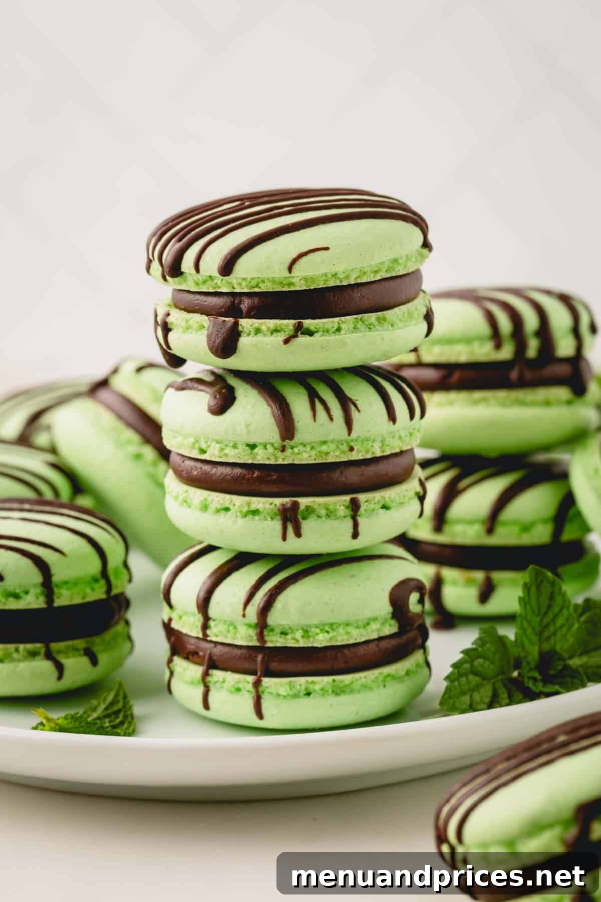 Minty Cocoa Macaron Bliss 24 A beautiful stack of three mint chocolate macarons, surrounded by a delightful collection of more vibrant green macarons, ready to be enjoyed.