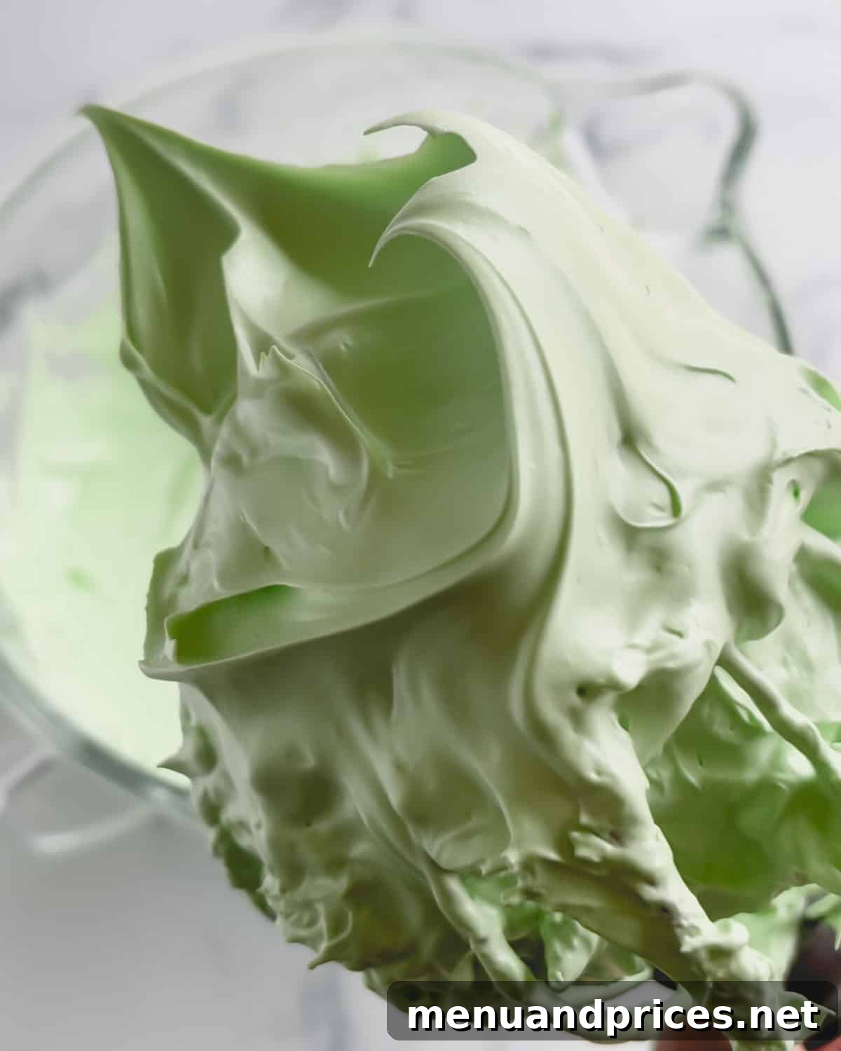 Minty Cocoa Macaron Bliss 6 A vibrant green meringue, whipped to stiff peaks, clings perfectly to the whisk, showcasing its ideal, stable texture.