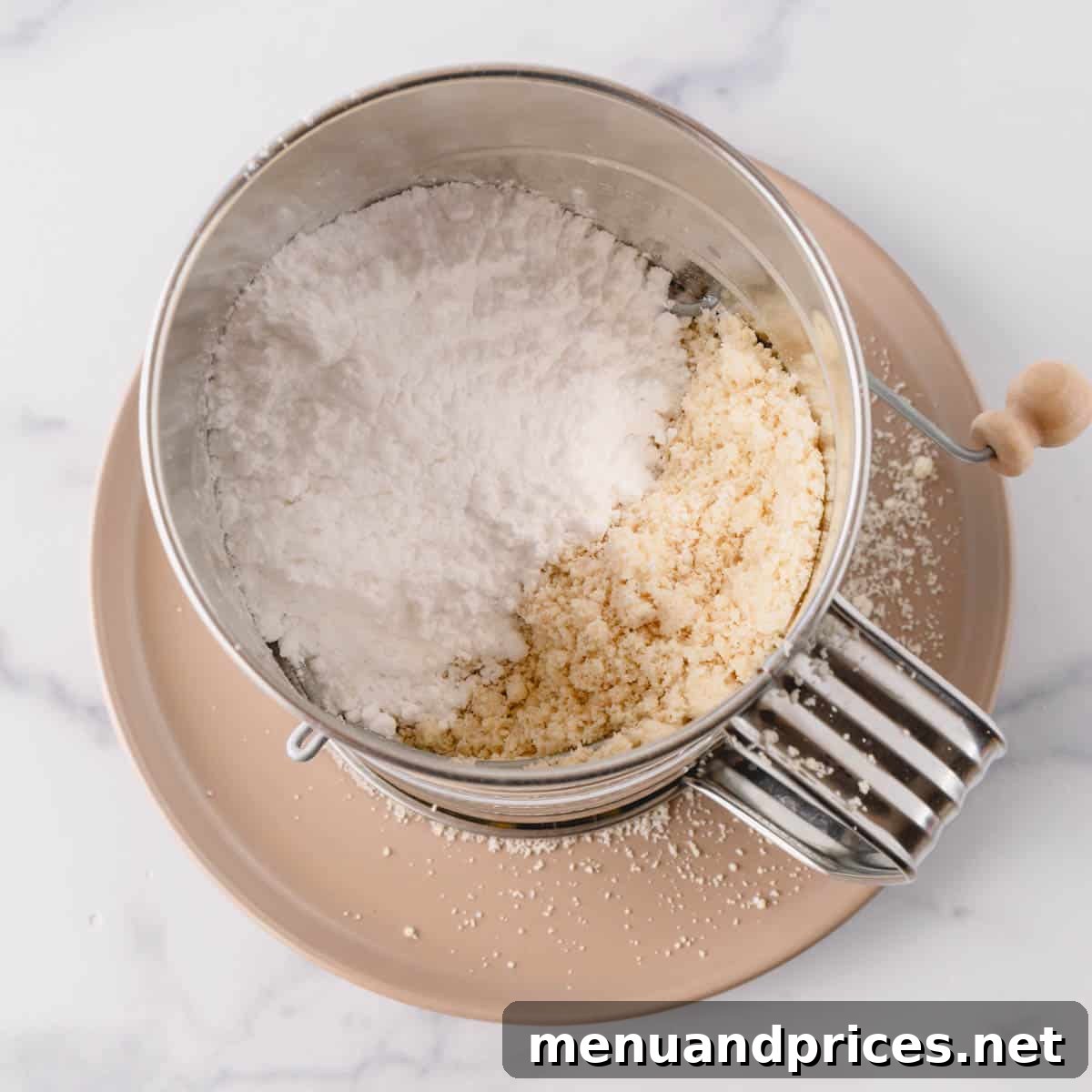 Minty Cocoa Macaron Bliss 7 Finely ground almond flour and powdered sugar are being loaded into a hand-crank sifter, ready for the crucial double sifting process.