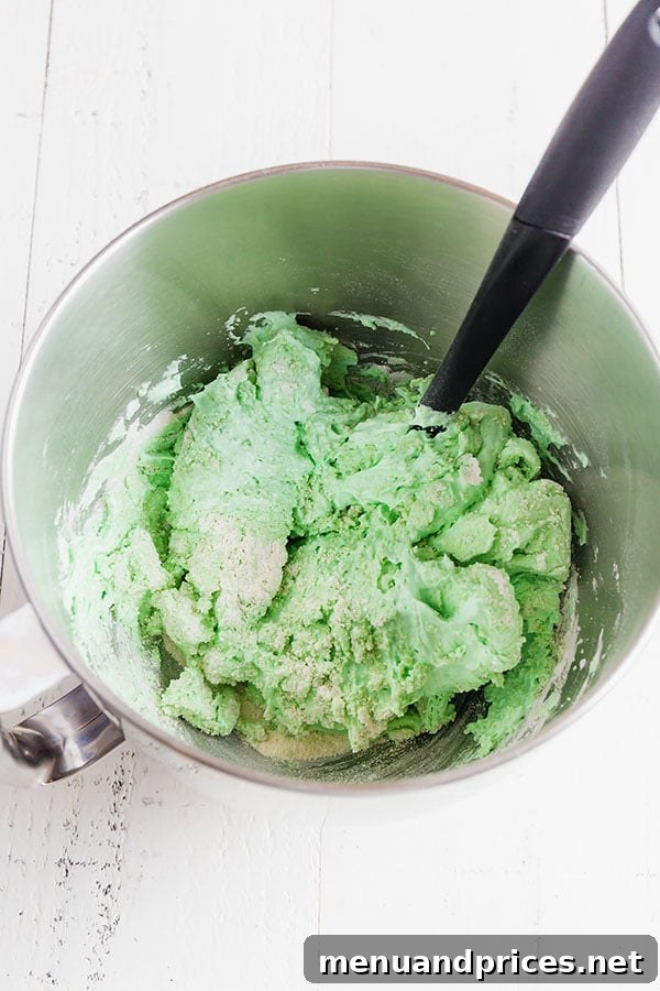 Minty Cocoa Macaron Bliss 9 The vibrant green meringue has been lightly mixed with the sifted dry ingredients in a stainless steel mixing bowl, beginning the macaronage process.