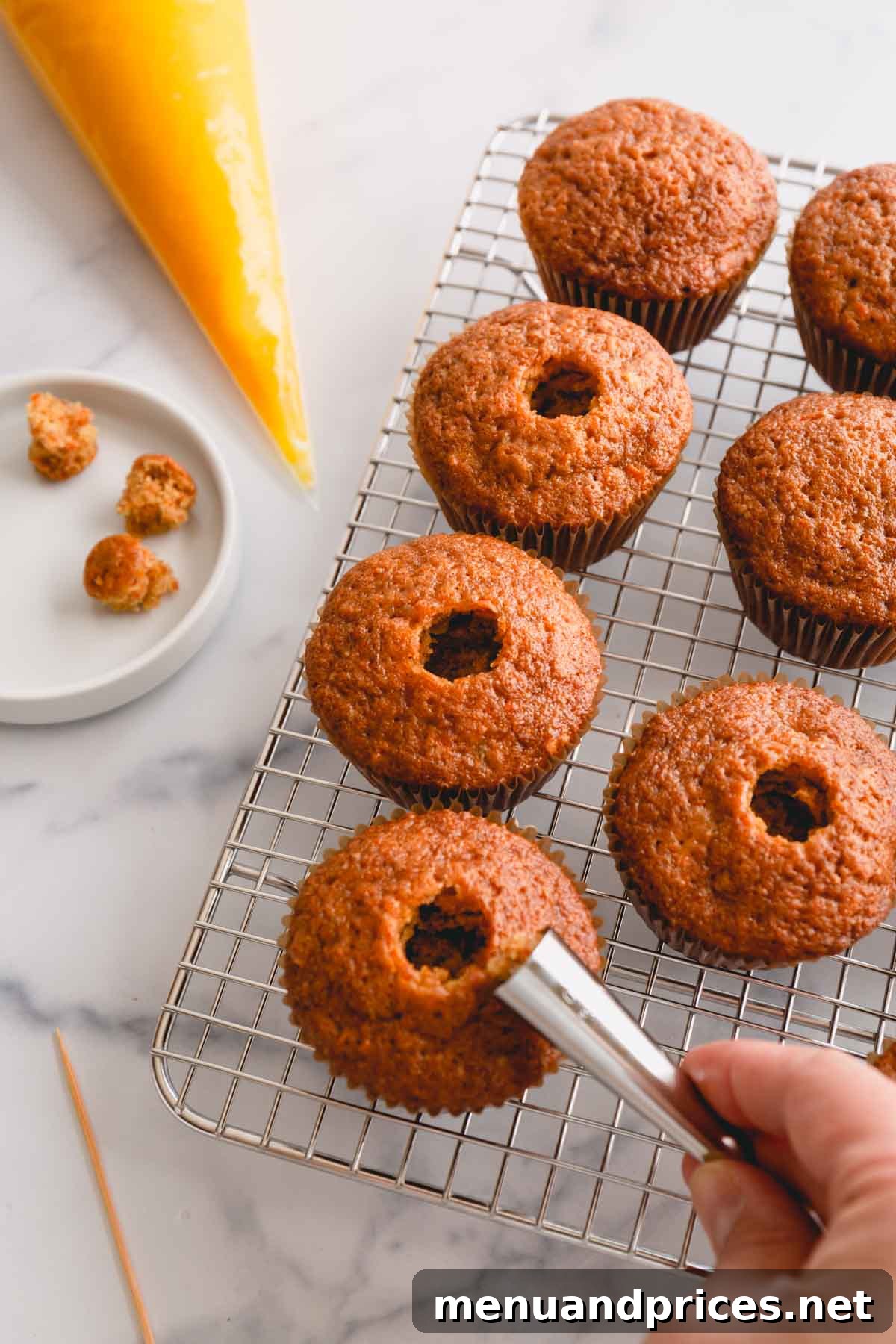 Spiced Carrot Cupcakes 11 Three perfectly baked carrot cupcakes, each with a carefully cored hole in the center, demonstrating preparation for filling.