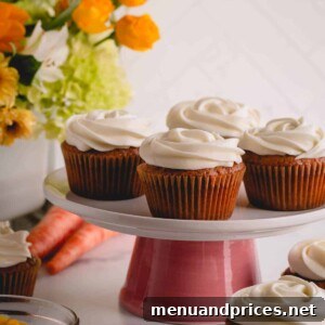 Spiced Carrot Cupcakes 14 A beautifully arranged tray of frosted carrot cake cupcakes, garnished with chopped pecans, ready to be enjoyed.