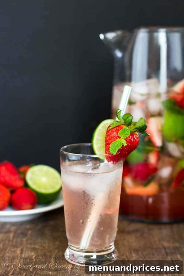 Garnished Strawberry Mojito glasses next to a pitcher