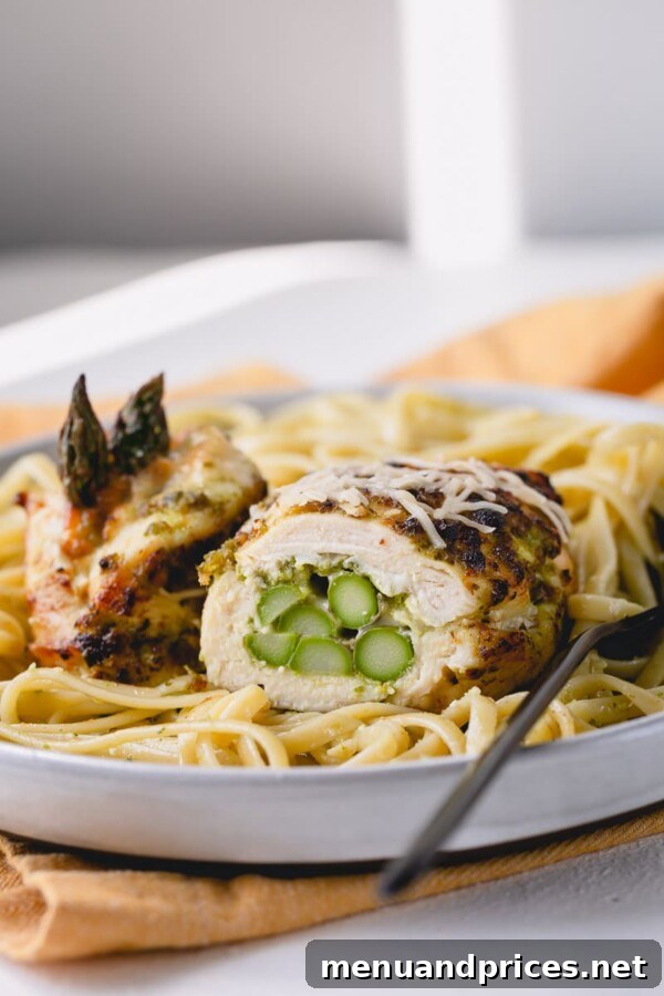 Close-up of a perfectly cooked pesto chicken roll-up, showcasing the melted cheese and visible asparagus.