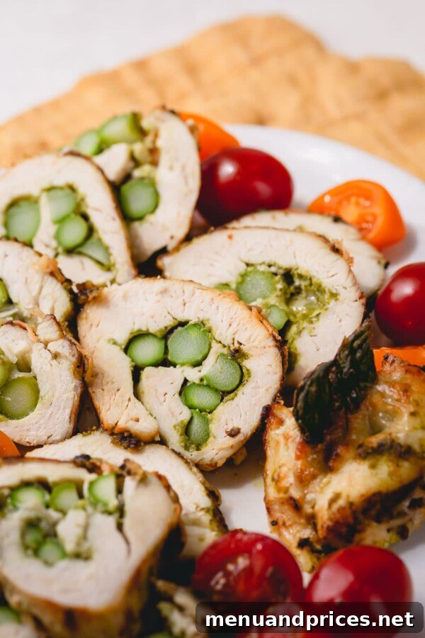 Pesto chicken and asparagus roll-ups sliced into appetizer portions, arranged on a platter with fresh garnishes.
