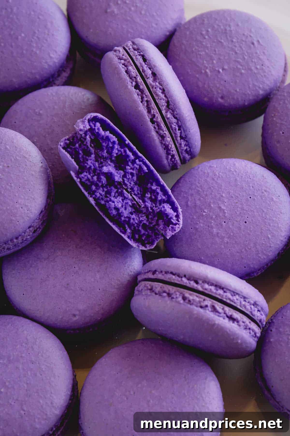 Secrets to Perfect Macaron Shells No More Hollows 4 Purple macaron shells with one cut in half exposing full interior, demonstrating a perfect, non-hollow macaron.