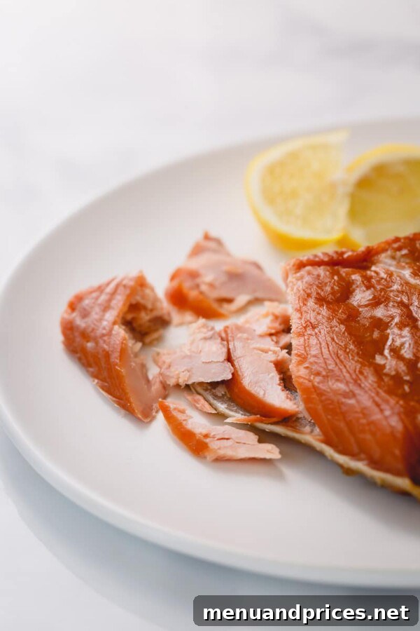 Smoked Salmon Silky Cold or Flaky Hot 4 A close-up view of flaky, fully cooked hot-smoked salmon, showcasing its opaque orange color and inviting, tender texture.