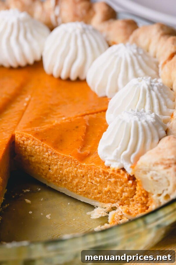 No-Fuss Pumpkin Pie Perfection 4 A beautifully composed image showing one whole pumpkin pie and a couple of slices, ready to be enjoyed.