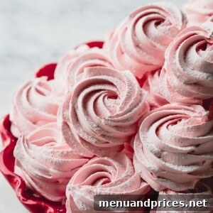 Pink rosette marshmallows stacked on a red plate, showcasing their delicate texture and appealing color.