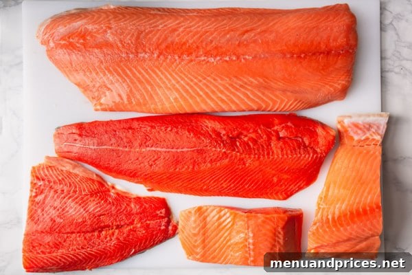 From Pink to King Exploring the Diverse World of Salmon 3 Close-up view of five different raw salmon fillets, showcasing their color variations and marbling, ready for cooking.