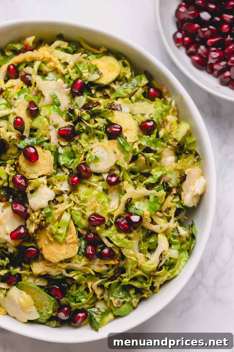 Brussels Sprout Ribbon Salad with Pomegranate 2 A beautifully presented bowl of shaved Brussels sprouts, glistening from the vinaigrette and adorned with vibrant pomegranate arils.