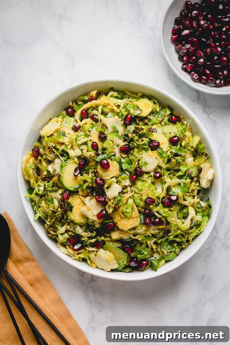 Brussels Sprout Ribbon Salad with Pomegranate 6 An inviting overhead shot of a large, rustic bowl filled with golden-brown roasted shaved Brussels sprouts, beautifully garnished with bright red pomegranate arils.
