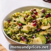 A bowl of roasted shaved Brussels sprouts topped with pomegranate arils.