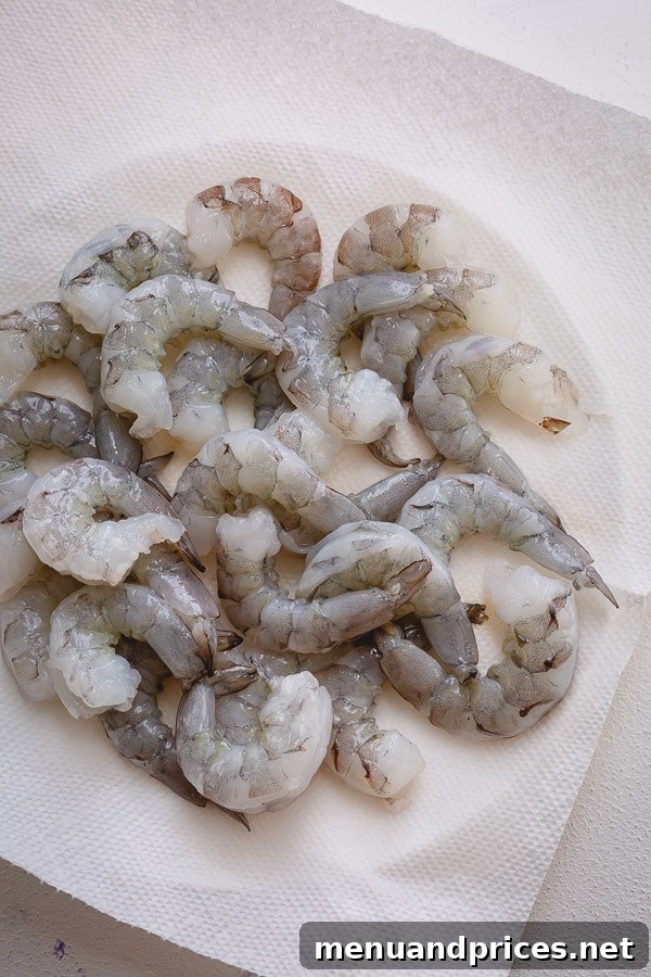 Perfectly Boiled Shrimp Every Time 5 Raw, peeled, and deveined shrimp laid out on a paper towel, ready for cooking.