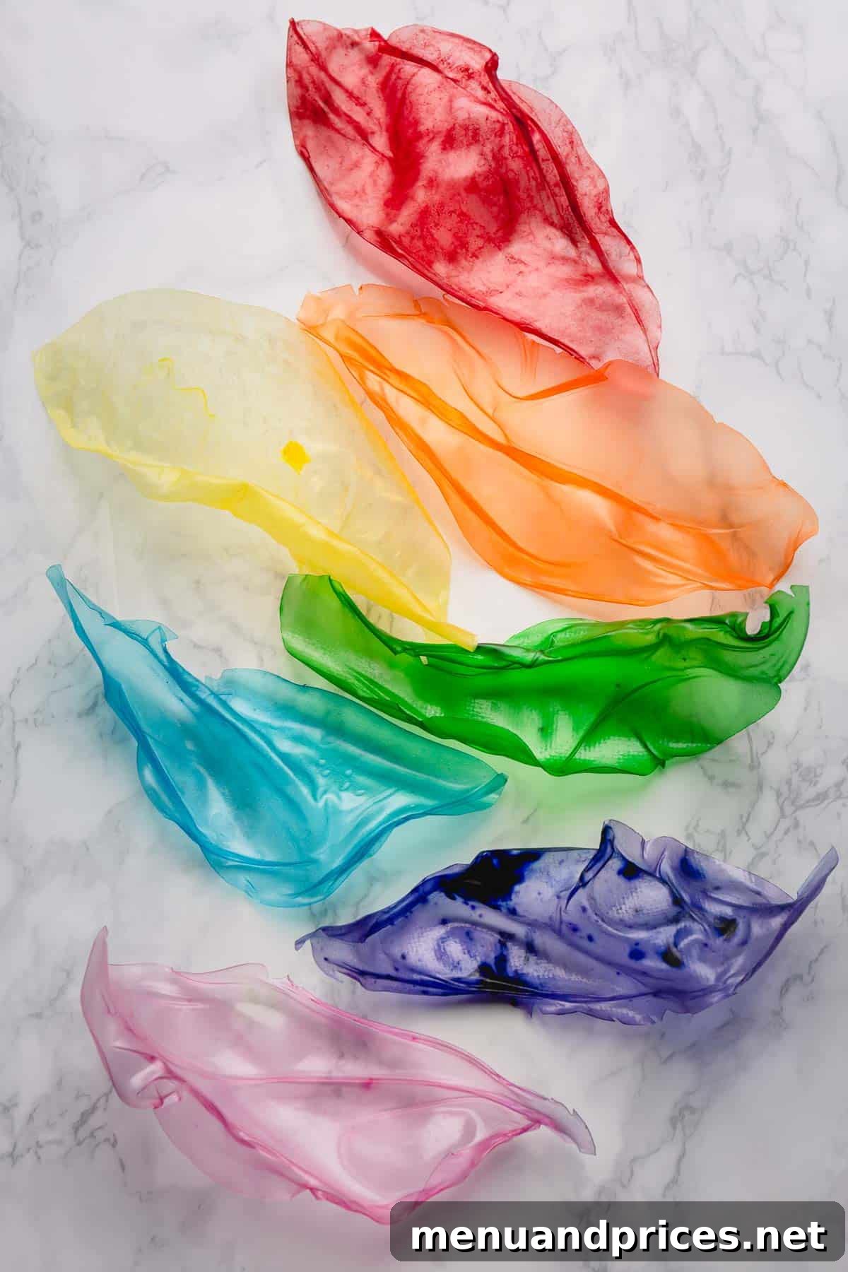Crafting Elegant Rice Paper Sails for Cake Art 3 A vibrant collection of seven rainbow-colored rice paper sails neatly arranged on a kitchen counter, highlighting their diverse shapes and delicate translucency.