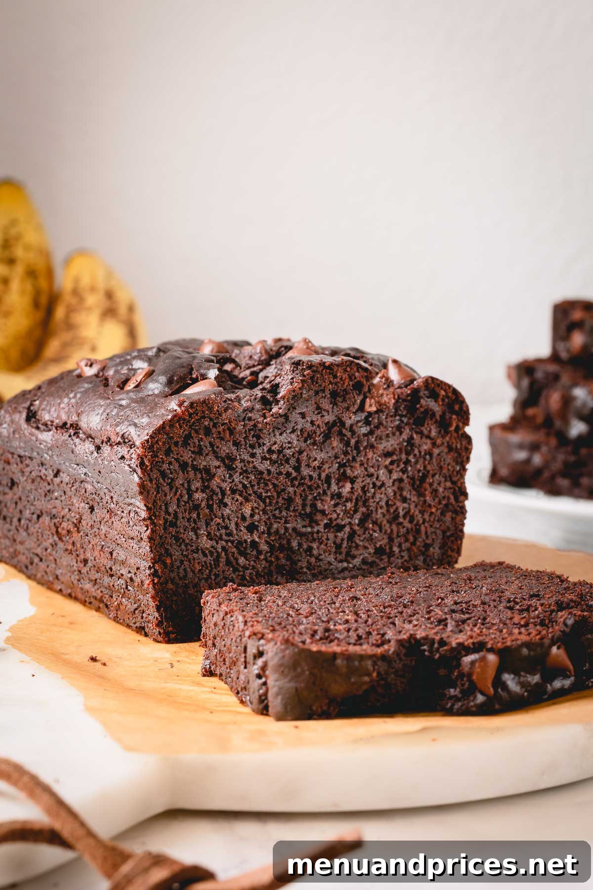 Fudgy Chocolate Banana Bread 3 A freshly baked loaf of chocolate banana bread with a single slice cut, showcasing its moist interior and chocolate chips.