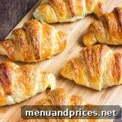 A final close-up of a single homemade croissant, showing its perfectly golden crust and flaky texture, inviting you to take a bite.