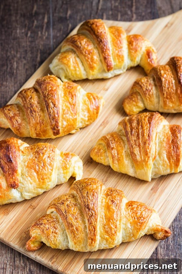 Flaky Homemade Croissants 2 A selection of freshly baked golden homemade croissants arranged invitingly on a wooden surface, highlighting their delicate layers and perfect crescent shapes.