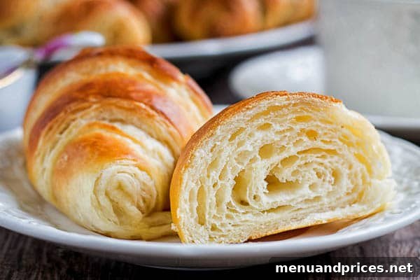 Flaky Homemade Croissants 3 A close-up shot of a single perfectly baked croissant, showcasing its rich golden-brown exterior and enticing texture.