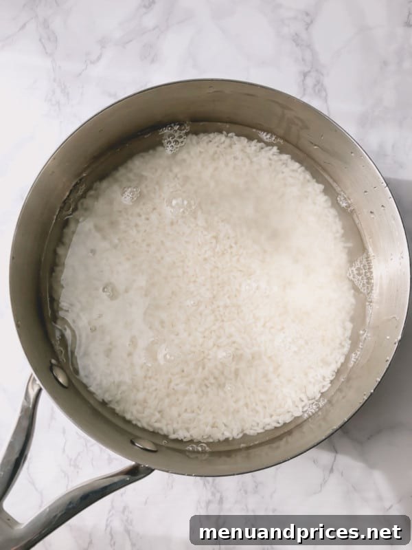 Unlock the Art of Sushi Rice 3 Washing short-grain sushi rice in a pan under cold water, highlighting the rinsing process