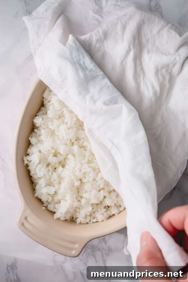 Unlock the Art of Sushi Rice 5 Seasoned sushi rice covered with a damp towel in a wooden hangiri to maintain moisture and texture