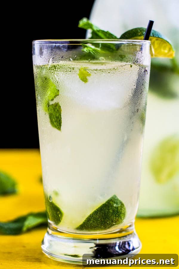 Tropical Bliss Coconut Mojito 4 Ingredients laid out for making a coconut mojito, including fresh mint, lime, rum, and sugar, on a light background.