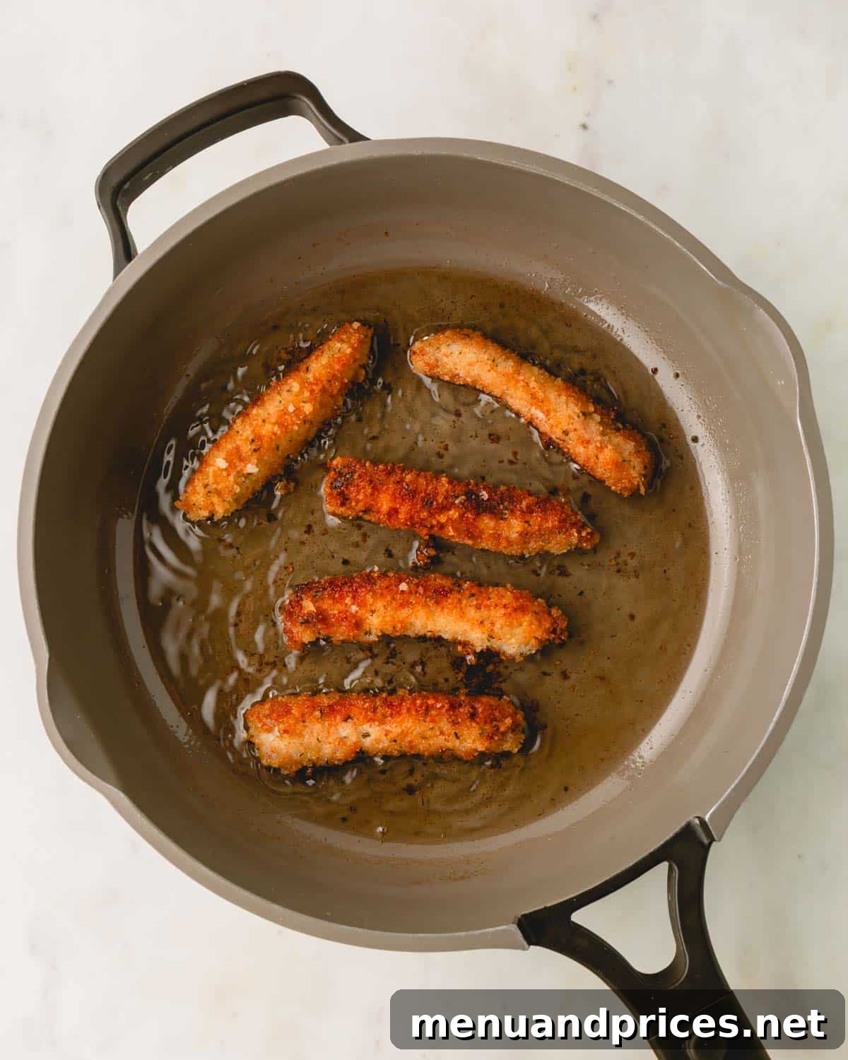 Crispy Golden Pork Strips 8 Cooked, golden-brown pork strips resting in a skillet after frying.
