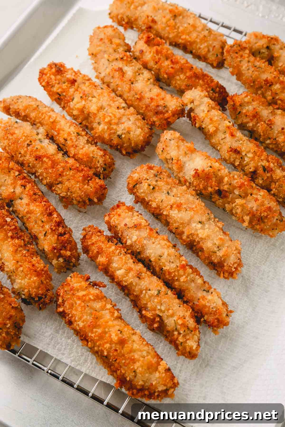 Crispy Golden Pork Strips 9 Crispy fried pork strips draining on a paper towel-lined wire rack.