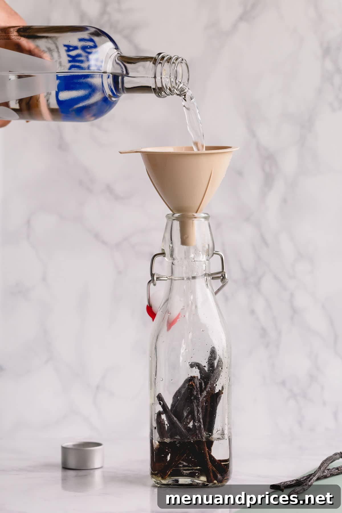 The Art of Homemade Vanilla Extract 5 Vodka being poured into a bottle containing vanilla beans, initiating the extraction process.