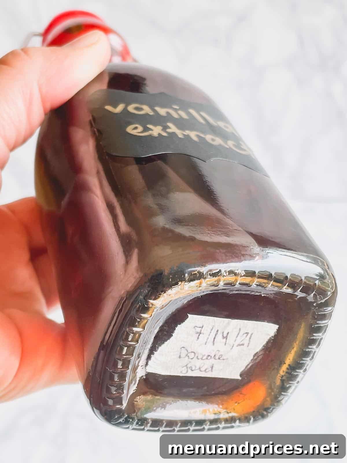 The Art of Homemade Vanilla Extract 7 A clear glass bottle of vanilla extract with a tape on the bottom displaying the creation date.