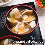 Two bowls of clam miso soup beautifully presented on a black tray, garnished with fresh green onions.